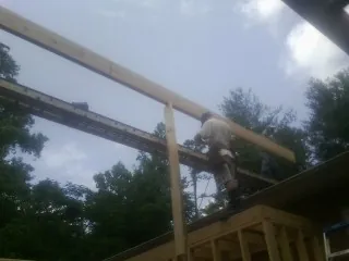 Carpenter setting a ridge beam over a new addition frame — Ice Dam Removal by Roofing Brothers in Spragueville
