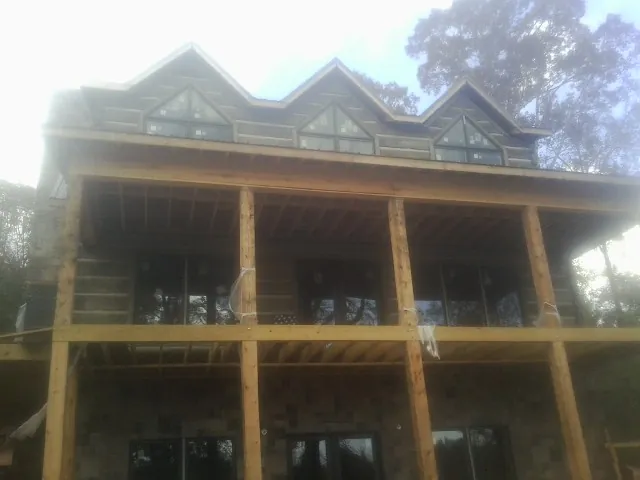 Dormers and porch framing on a large log home under construction — Roof Coating work by our crew in Spragueville