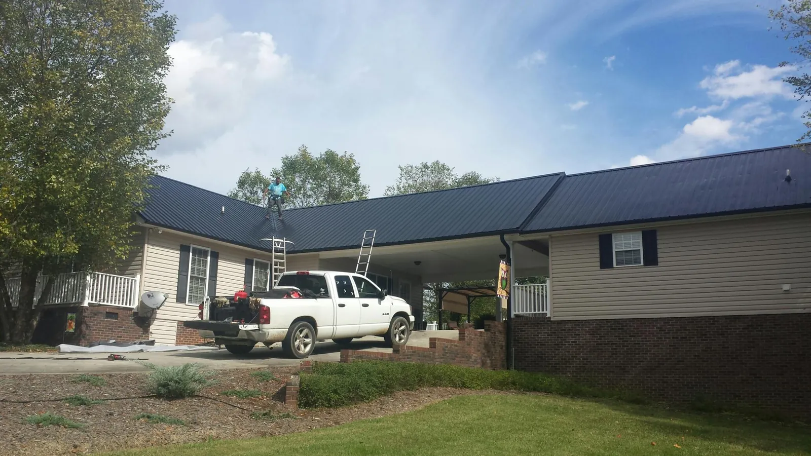 Black metal roof over a home and attached breezeway with ladders set in Spragueville