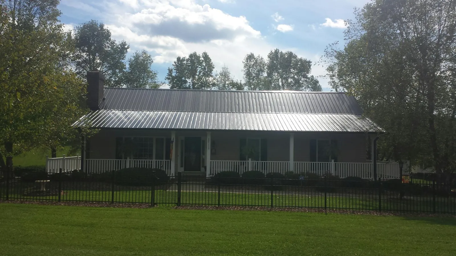 Gray metal roof on a brick ranch with a full width front porch — Gutter Guard Installation work by our crew in Spragueville