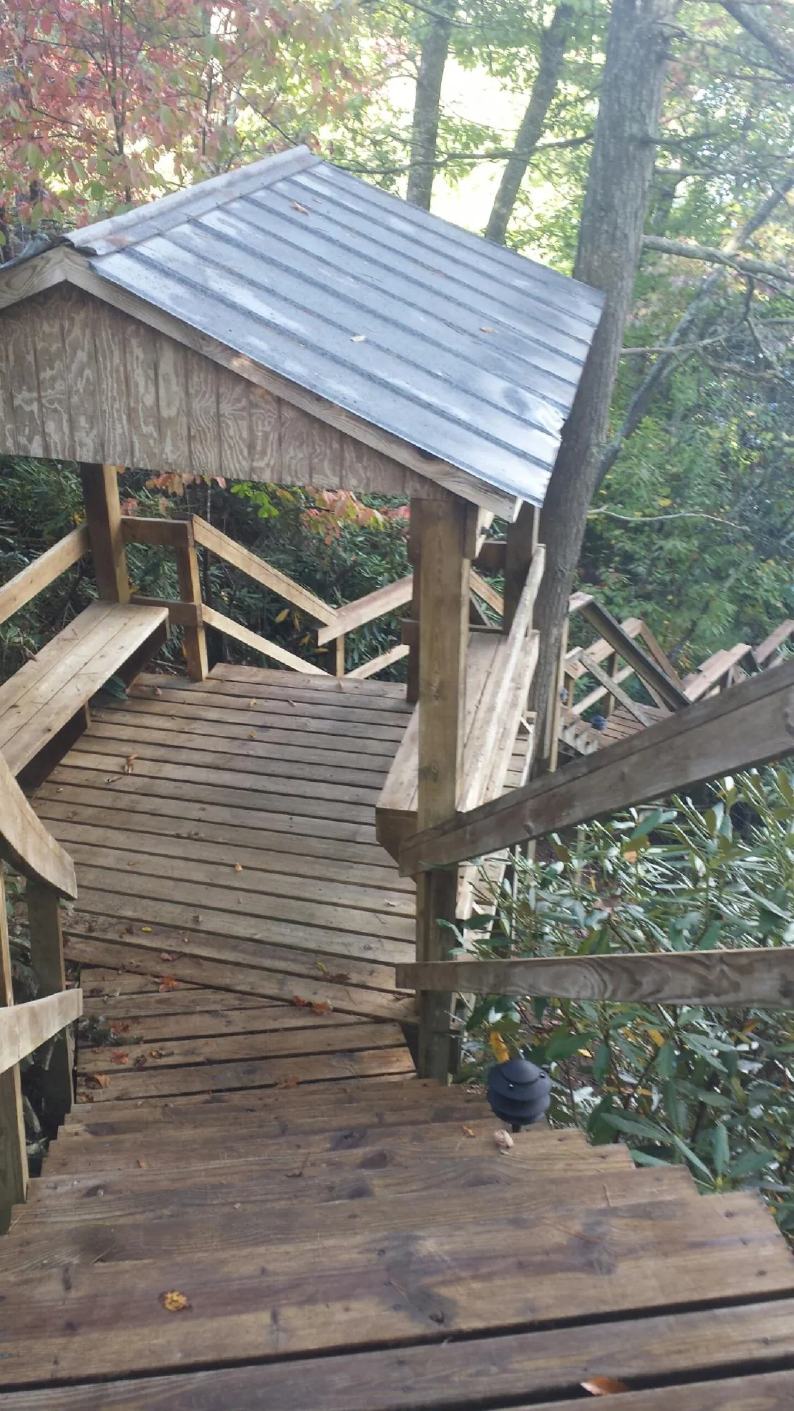 Metal roofed shelter over wooden steps on a wooded walkway — Skylight Repair & Installation work by our crew in Spragueville