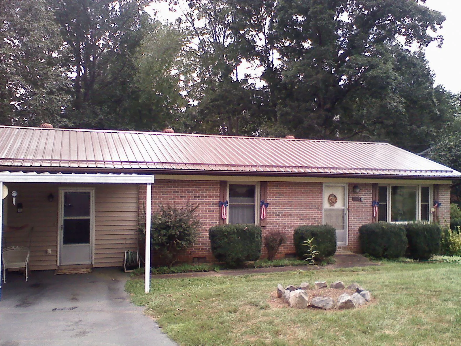 Bronze metal roof and carport on a brick ranch home — Roof Repair work by our crew in Spragueville