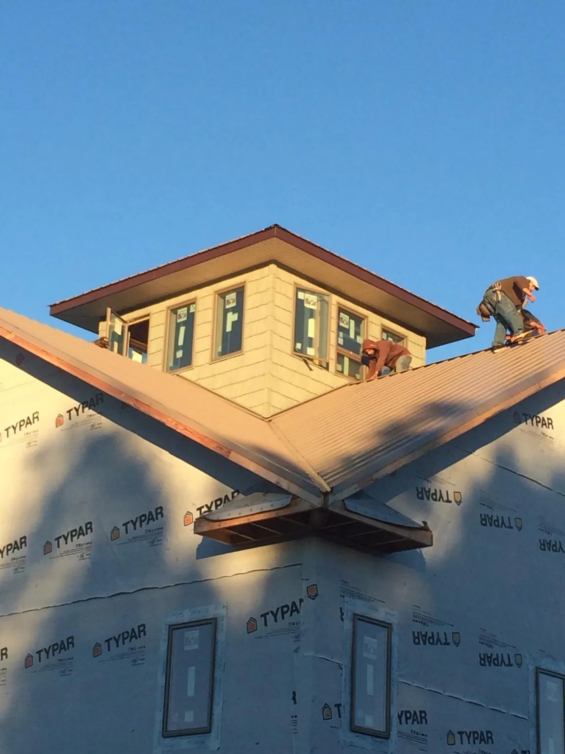 Roofers working around a rooftop cupola on a new metal roof at sunset — Roof Waterproofing in Spragueville by Roofing Brothers